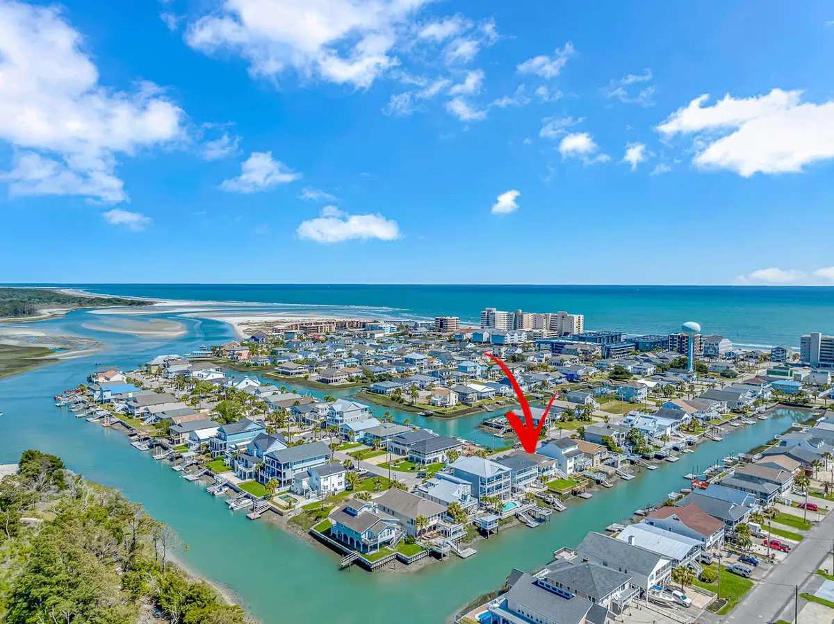 A tranquil view of the canal waterways, surrounded by residential homes and a distant beachfront beneath a broad sky. The scene suggests easy access to both water activities and beach outings, aligning with the narrative of exploring nearby dog beaches and local attractions.