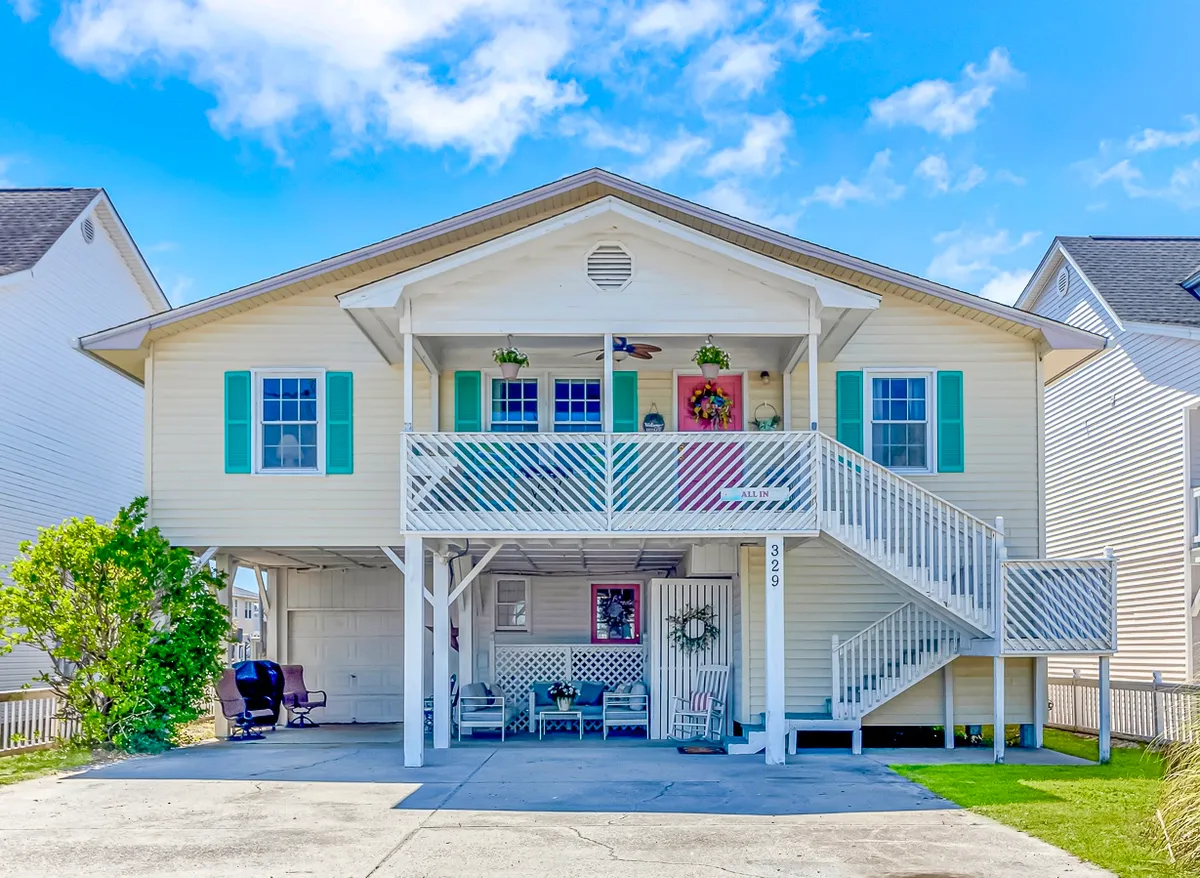 The hero image showcases the vibrant exterior of a cheerful, beach-inspired single-family home, featuring a welcoming front porch with comfortable seating, colorful shutters, and a decorative wreath. The scene invites relaxation and social gatherings, with hints of waterfront scenery peeking through. The setup suggests an inviting atmosphere perfect for families, groups, and pet lovers.