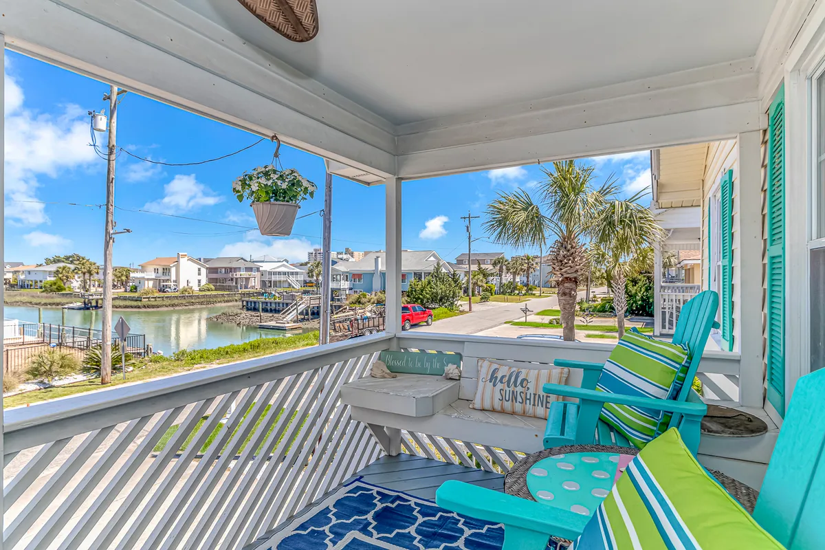 A bright and cheerful exterior space with colorful chairs, a hanging plant, and a decorative sign. The setup hints at afternoons spent relaxing, socializing, and watching boats pass, creating a lively and welcoming atmosphere for group gatherings.