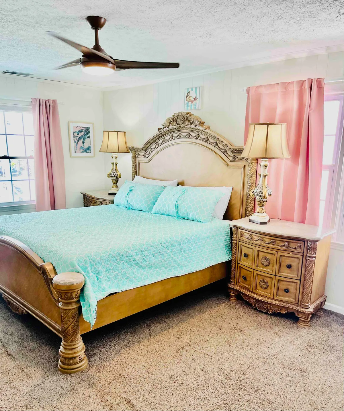 A serene bedroom featuring a plush bed flanked by nightstands and lamps, with decorative art lending a restful ambiance. The overall vibe is calm and inviting, ideal for unwinding after a day by the water.